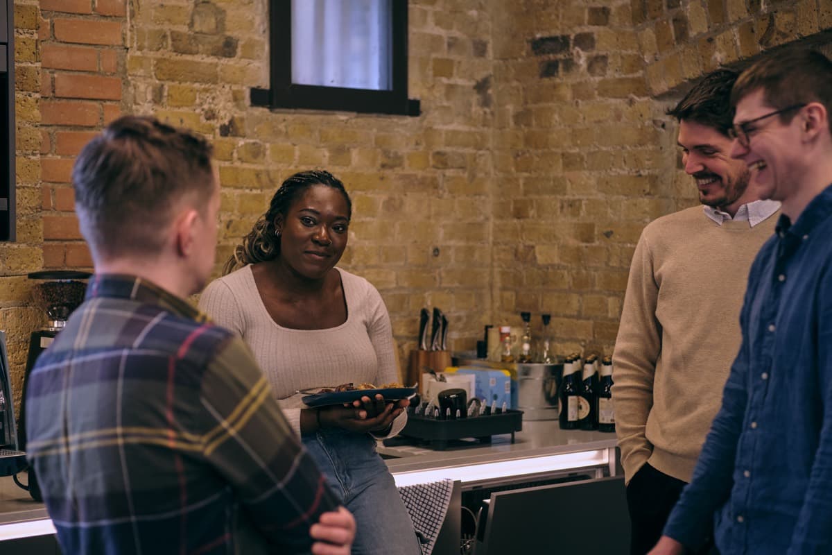 People chatting and laughing by the studio kitchen, food and drinks on the counter